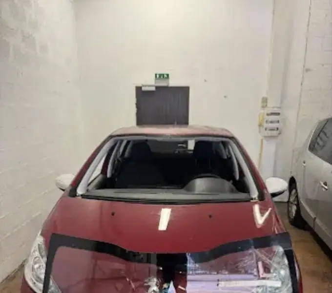 Ancien pare-brise retiré sur une Peugeot rouge